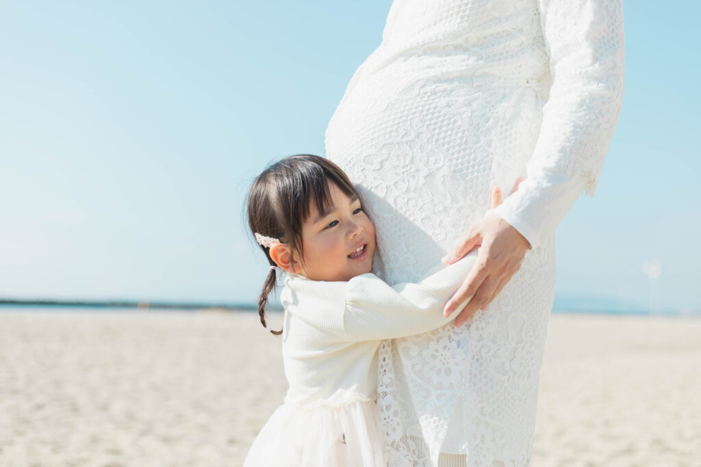 お腹の中の赤ちゃんにハグするお姉ちゃんの写真1