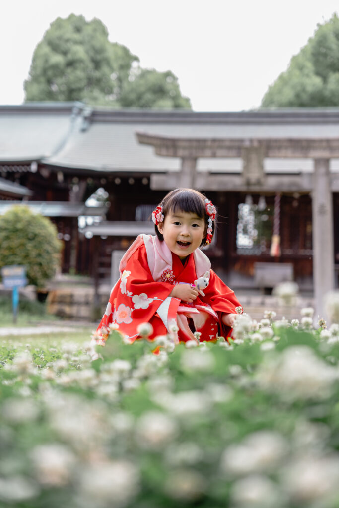 神社の中のお花畑でニコニコする女の子の写真1