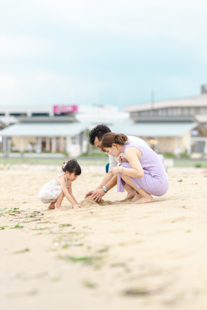 海で砂山を作る家族の写真