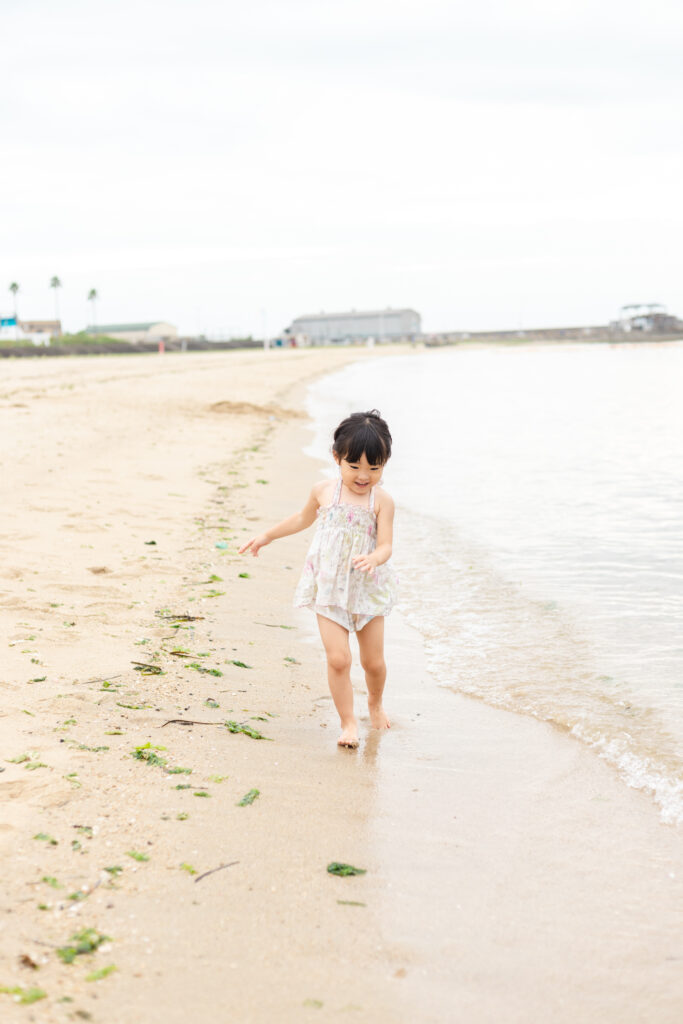 海を笑顔で歩く子供の写真